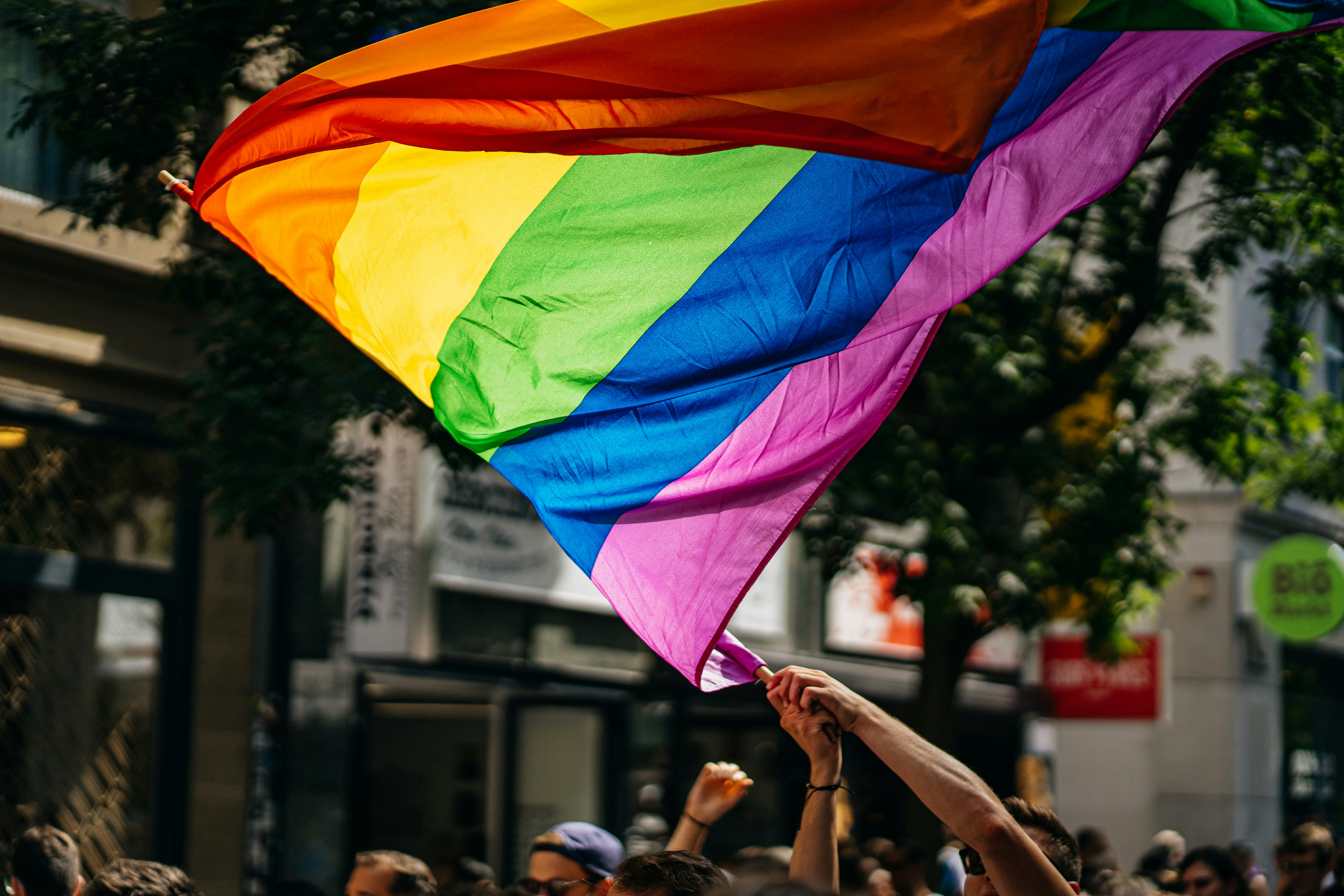 A pride march with someone waving a large rainbow price flag